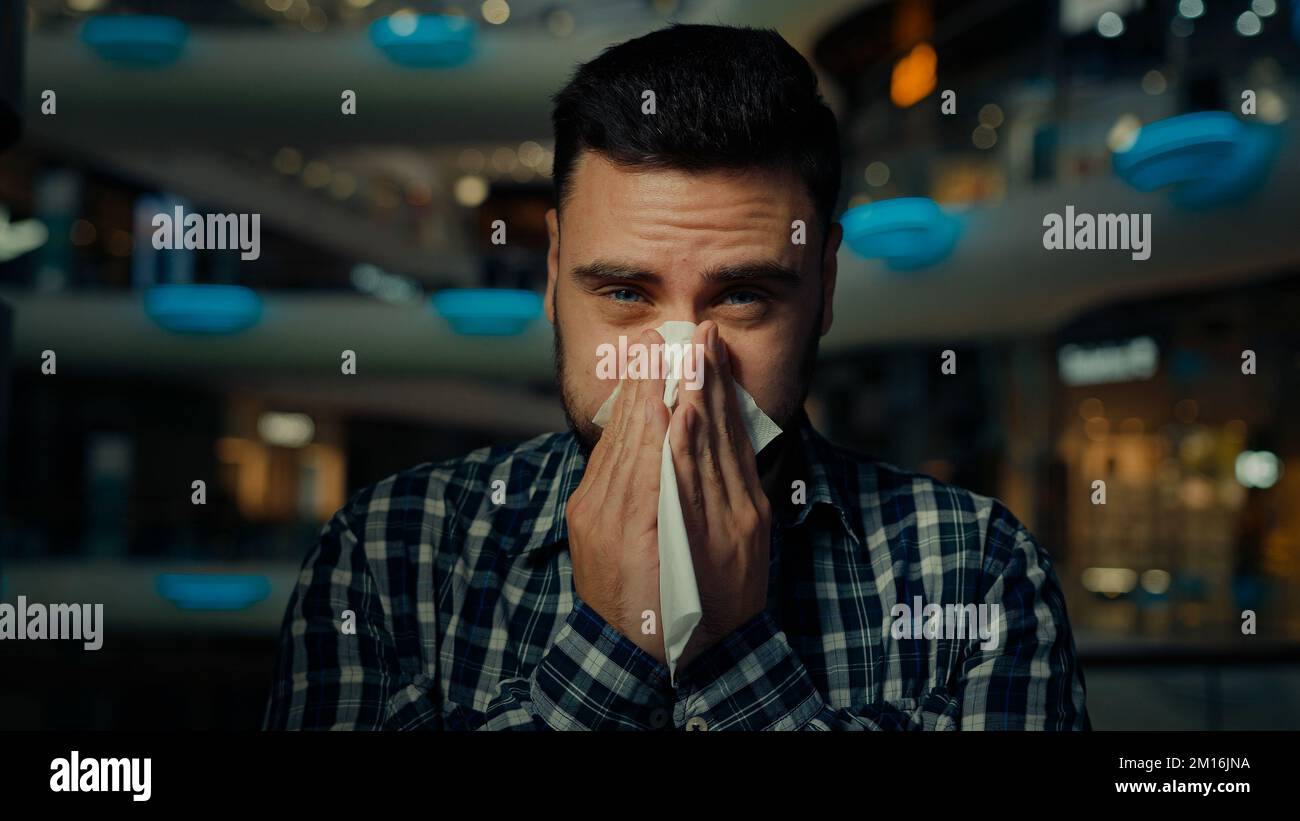 Kranker arabischer Mann junger männlicher allergischer Kerl im Einkaufszentrum leiden an laufender Nase Grippe-Krankheit saisonale Allergie Mund Niesen Nase mit Stockfoto