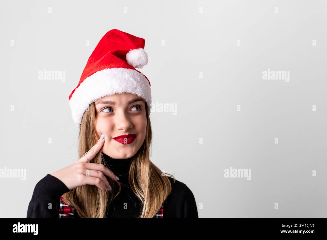 Hübsches, junges, blondes Mädchen mit Weihnachtsmannmütze, isoliert auf weißem Hintergrund, denkt. Speicherplatz kopieren Stockfoto