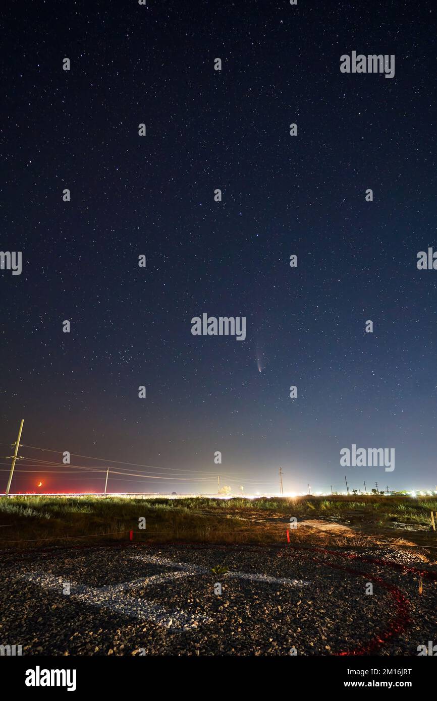 Echtes Sternenfoto von Neowise Comet C2020 F3 NEOWISE bei Mondaufgang. Neumond Halbmond am Horizont über dem Hubschrauberlandeplatz oder Heliport. Henychensk, Ukraine an Stockfoto