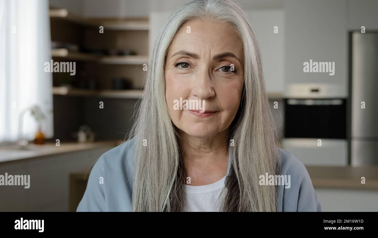 Portrait ruhig selbstbewusst Erwachsene mittleren Alters Frau Rentner Oma Herrin Hausbesitzer zärtliche reife alte Dame mit langen grauen Haaren posiert in Küche Zimmer Stockfoto