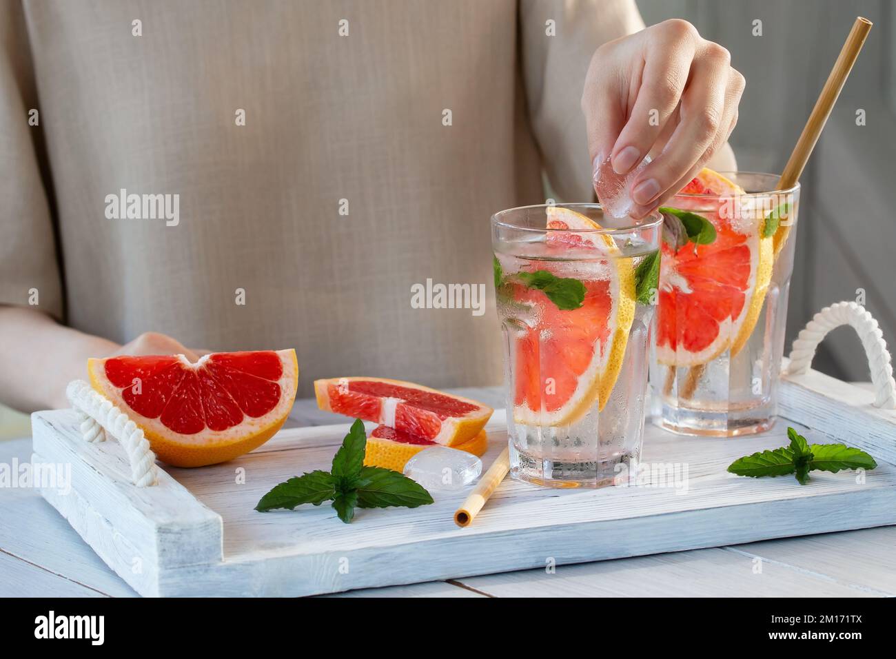 Mädchen Kochen Sommer erfrischenden Fruchtcocktail mit Grapefruit Scheiben und Minze. Stockfoto