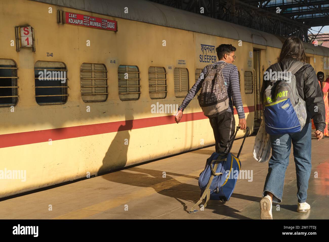 Eisenbahnpassagiere, die an den Waggons eines Fernzugs am Chhatrapati Shivaji Maharaj Terminus in Mumbai, Indien vorbeifahren Stockfoto