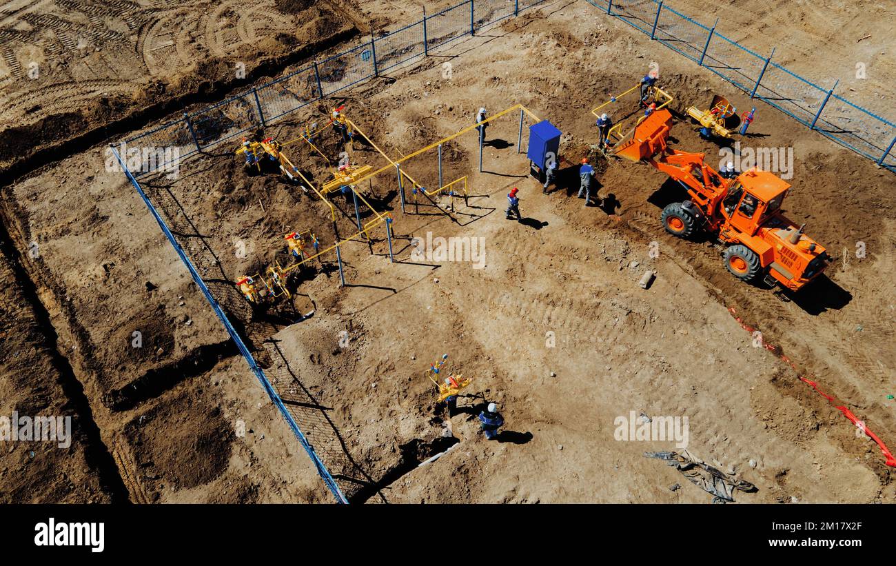 Bagger mit Luftaufnahme und Bauarbeiter, die auf der Baustelle im Freien arbeiten. Rohrverlegung im Graben zur Vergasung. Top-Punkt der Aufnahme. Reparatur und Wiederherstellung der Erdgasversorgung. Stockfoto