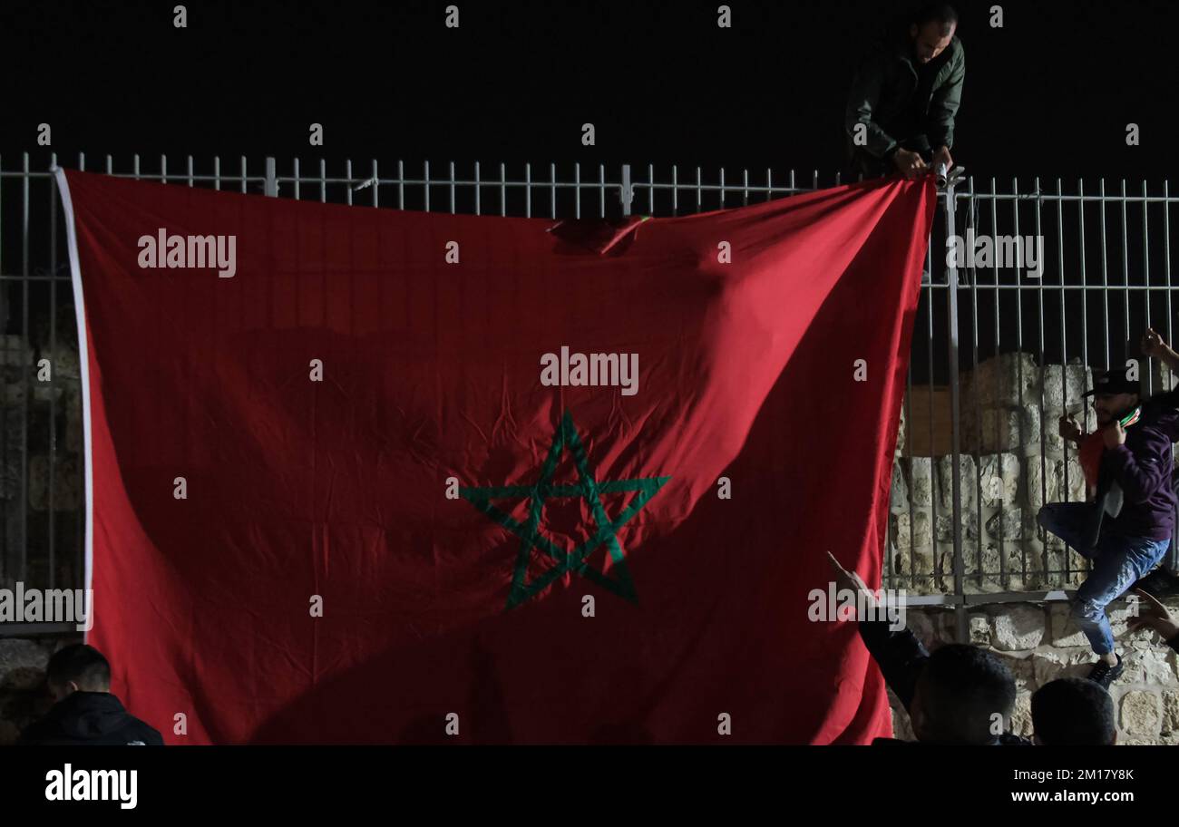 JERUSALEM, ISRAEL - DEZEMBER 10: Junge Palästinenser hängen eine große marokkanische Flagge auf, während sie den Sieg Marokkos gegen Portugal nach dem 2022. Quartal FIFA-Finalspiel Katar zwischen Marokko und Portugal in der Altstadt am 10. Dezember 2022 in Jerusalem, Israel, feiern. Marokko ist die erste afrikanische Seite, die nach Portugal in Katar am Halbfinale der FIFA-Weltmeisterschaft teilnimmt. Kredit: Eddie Gerald/Alamy Live News Stockfoto