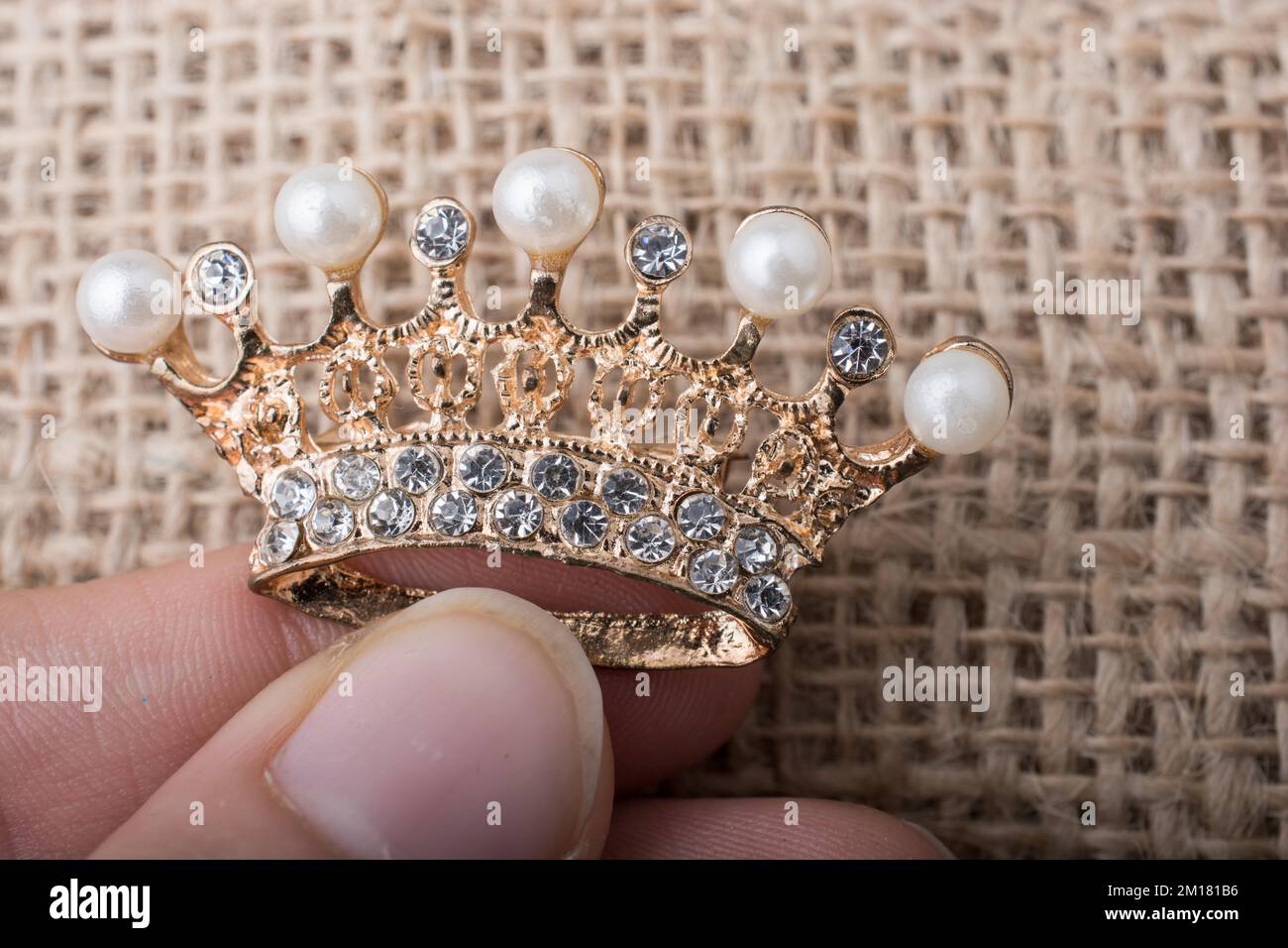 Goldene Krone-Farbmodell mit Perlen auf braunem Hintergrund Stockfoto