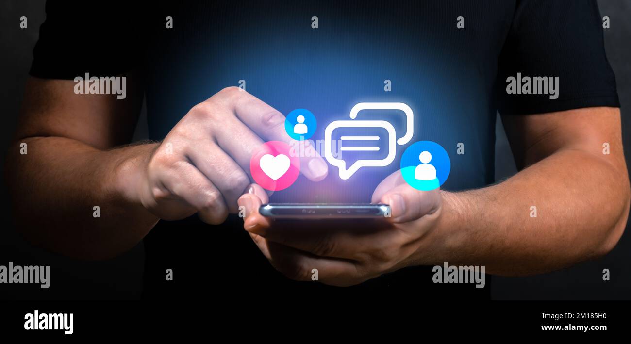 Ein Mann hält ein Smartphone mit virtuellem Social-Media-Symbol in der Hand. Männliche Hände und Handys mit Social Media und digitalem Online-Konzept. Nahaufnahme, dunkler Rücken Stockfoto