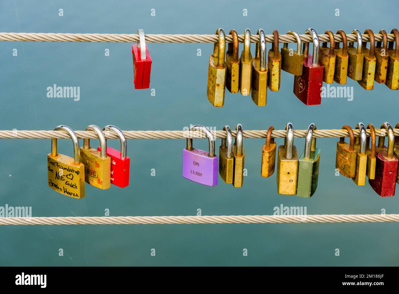 Viele farbenfrohe Schlösser sind an einem Stahlseil für ein Liebesgelübde verriegelt Stockfoto