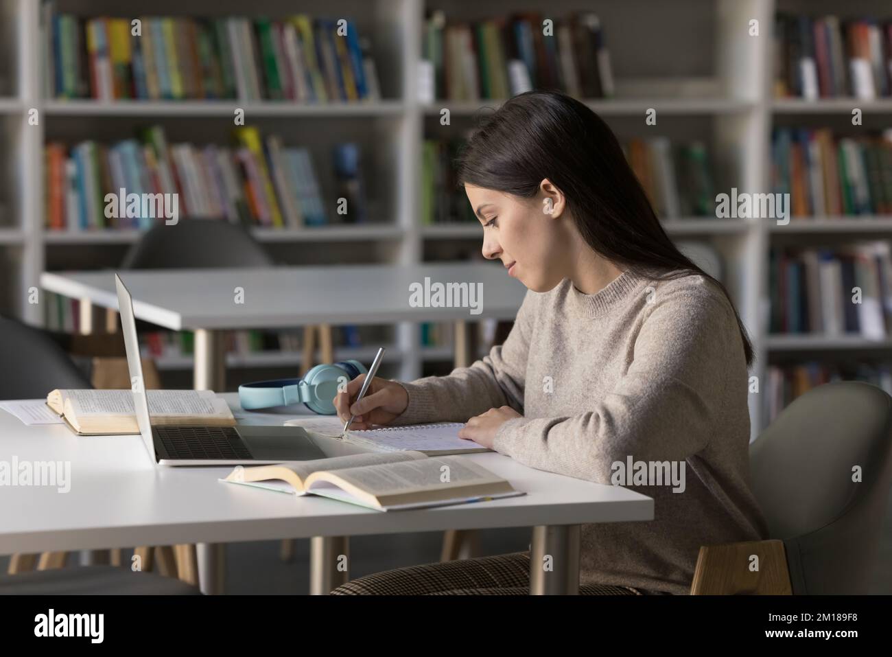 Fokussiertes, hübsches Studentenmädchen, das in einer öffentlichen Bibliothek lernt Stockfoto