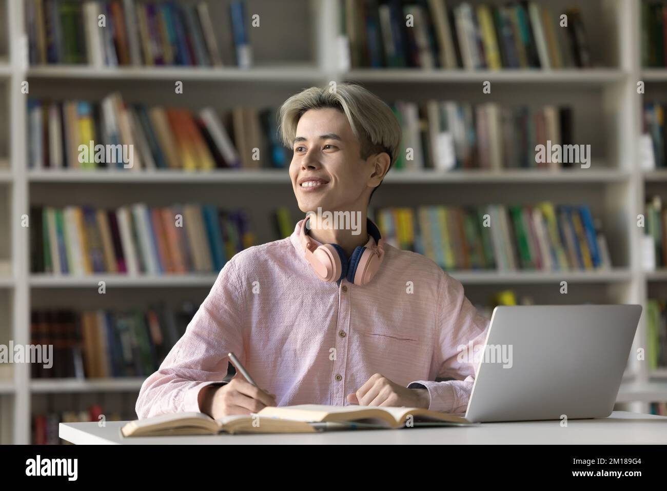 Freudiger asiatischer Teenager-Student, der Hausaufgaben in der Collegebibliothek macht Stockfoto