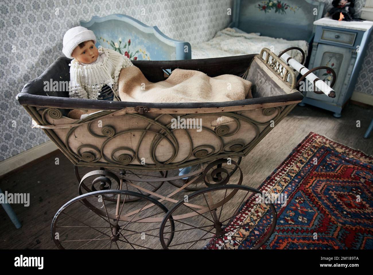Antiker Kinderwagen mit Babypuppe im alten Schlafzimmer Stockfoto