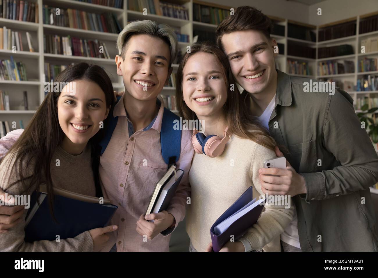 Glückliche, vielfältige Studenten, die für Gruppenporträts in der öffentlichen Bibliothek stehen Stockfoto