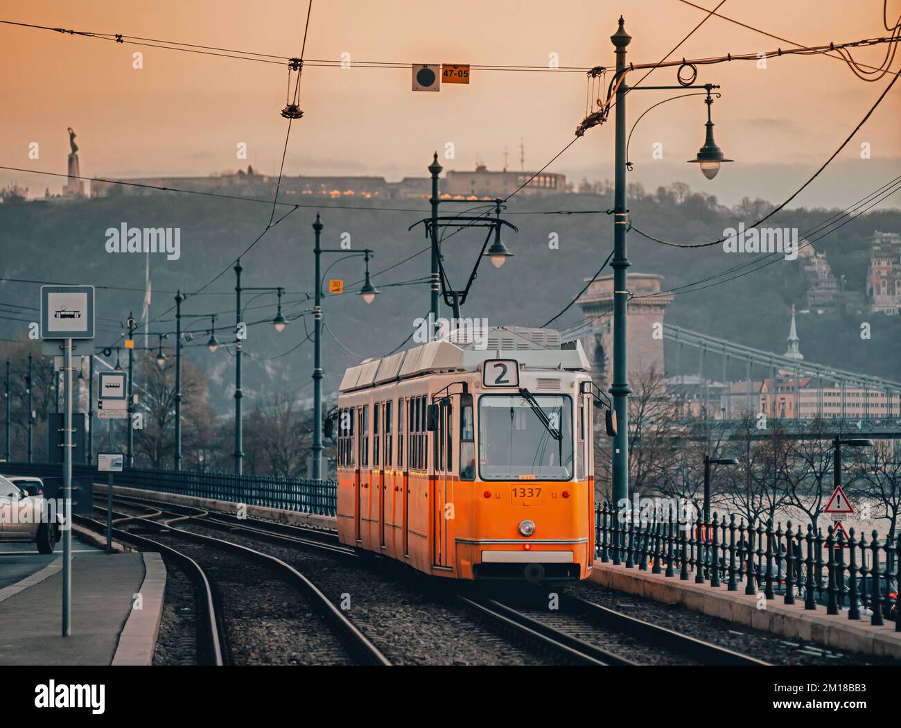 Eine alte Straßenbahn in der Nähe der Donau in Budapest. Die Straßenbahnlinie 2 mit alten Autos ist eine beliebte Touristenattraktion. Blick auf die Altstadt bei Sonnenuntergang. Stockfoto