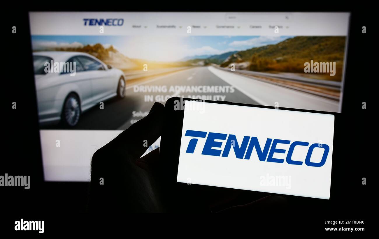 Person, die ein Mobiltelefon mit dem Logo des US-amerikanischen Automobilunternehmens Tenneco Inc. Auf dem Bildschirm vor der Unternehmenswebseite hält. Konzentrieren Sie sich auf das Display des Telefons. Stockfoto