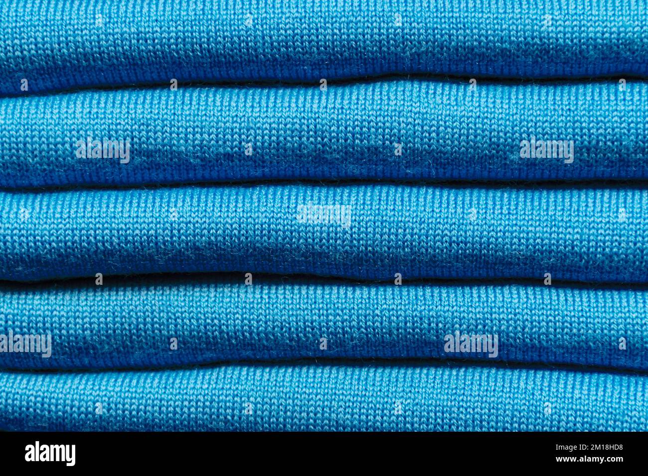 HINTERGRUNDSTRUKTUR – aus gefalteten Stücken aus blauem Strickstoff Stockfoto