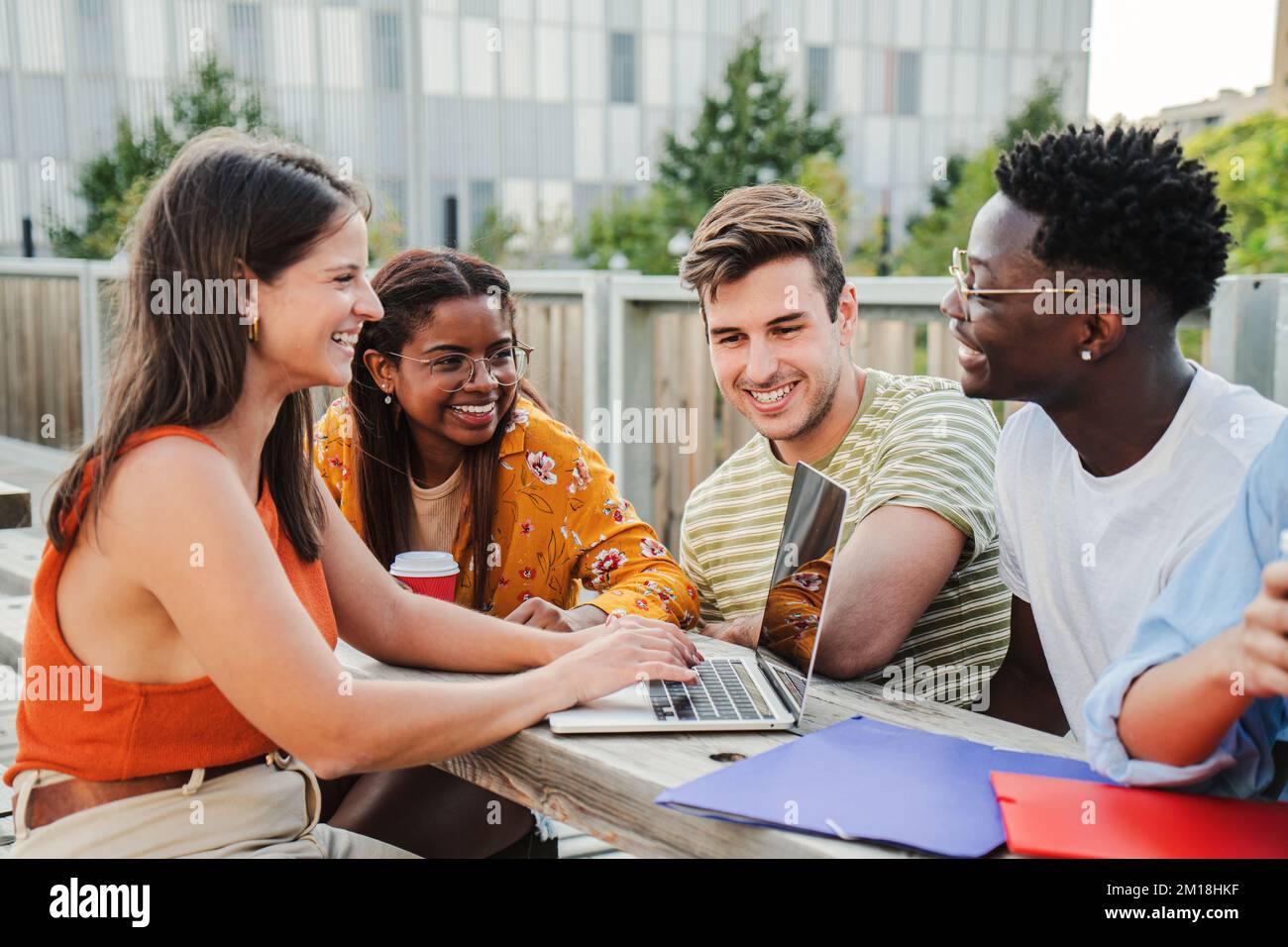 Eine multiethnische Gruppe glücklicher und lächelnder junger Schüler, die eine Prüfung vorbereiten und Hausaufgaben machen, und verschiedene Ideen mit ihren Laptops teilen, in positiver und freundlicher Kommunikation auf dem Campus. Bildungskonzept. Hochwertiges Foto Stockfoto