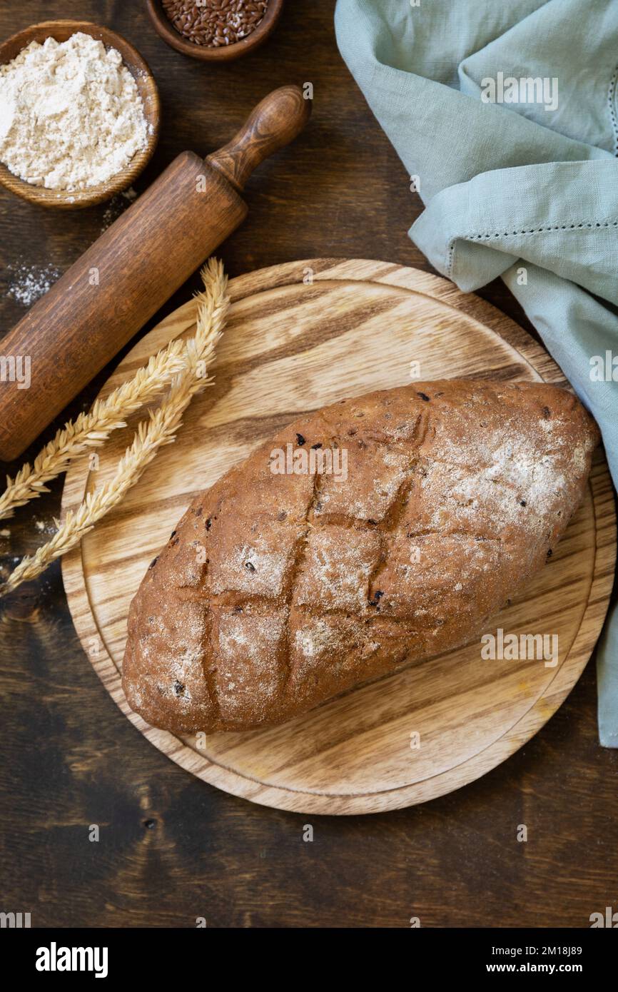 Hausgemachtes Backen. Brot aus Vollkorn, Weizenkleie, Samen, Bio-Zutaten über rustikalem Tischhintergrund, gesunder Lebensstil. Blick von oben. Stockfoto