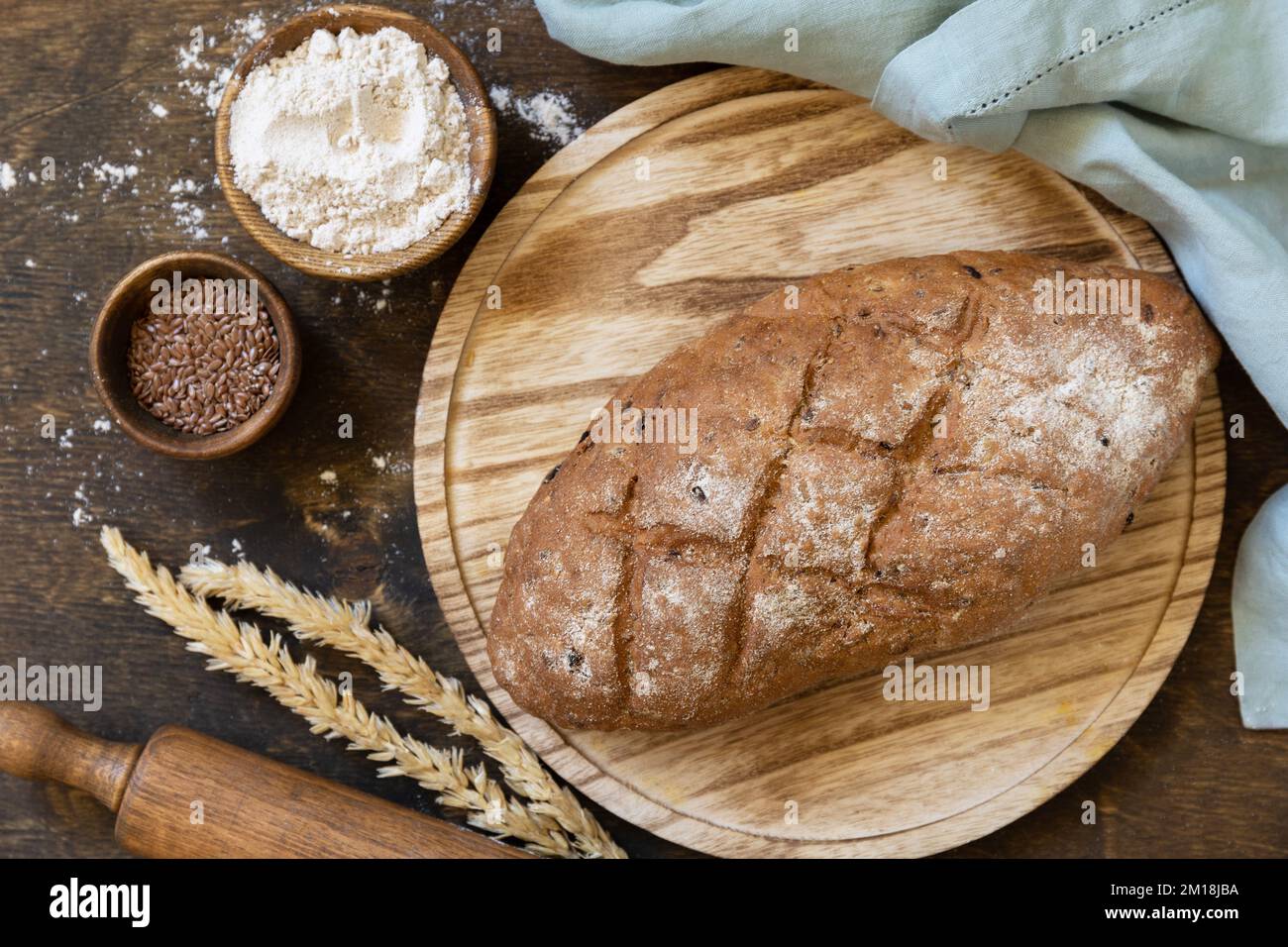Brot aus Vollkorn, Weizenkleie, Samen, Bio-Zutaten auf rustikalem Tischhintergrund. Hausgemachtes Backen, gesunder Lebensstil. Blick von oben. Stockfoto