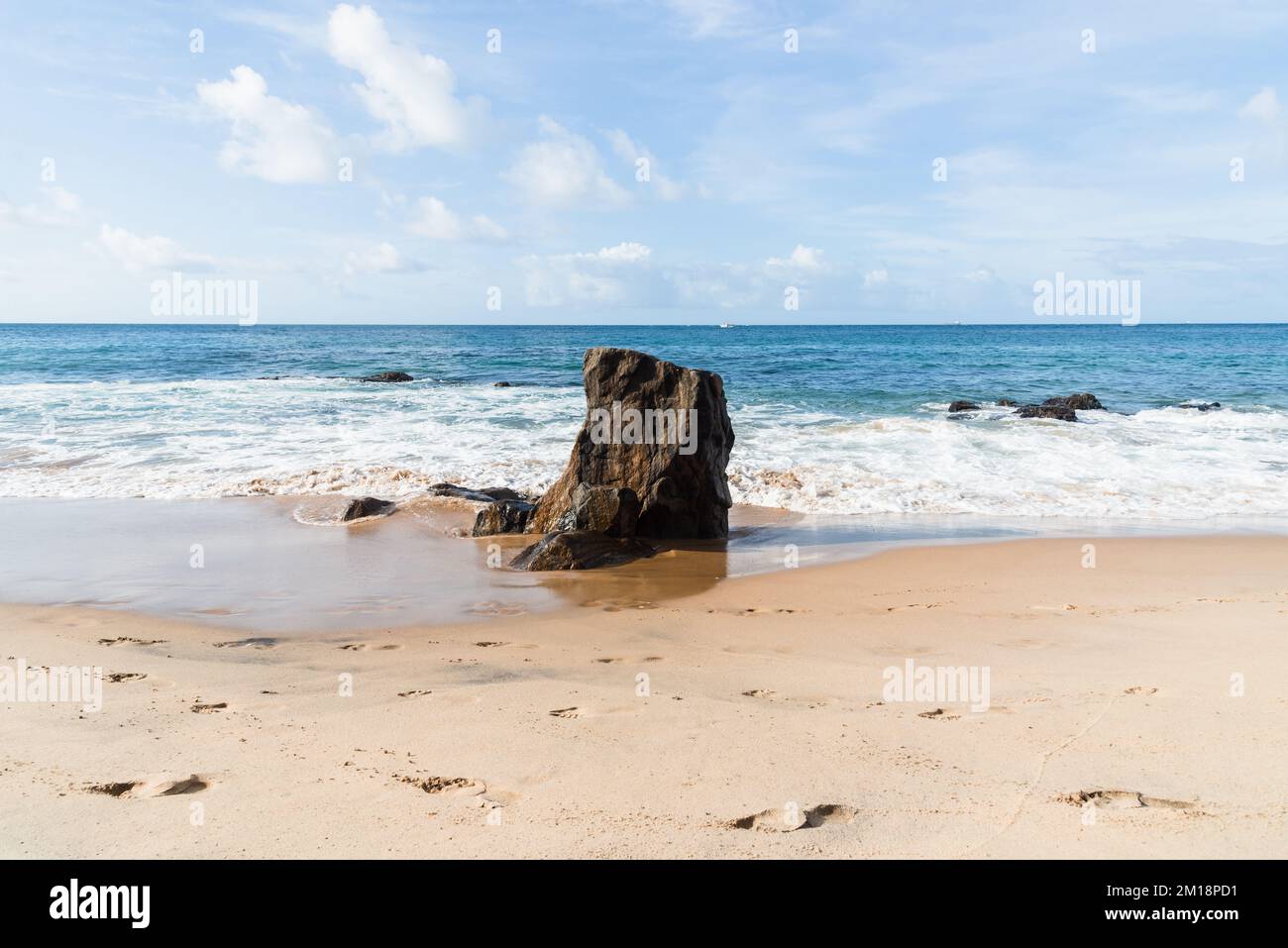 Während eines Vorhangs am Meer bricht eine Welle um einen Felsen. Farol da Barra Beach, Salvador, Brasilien. Stockfoto