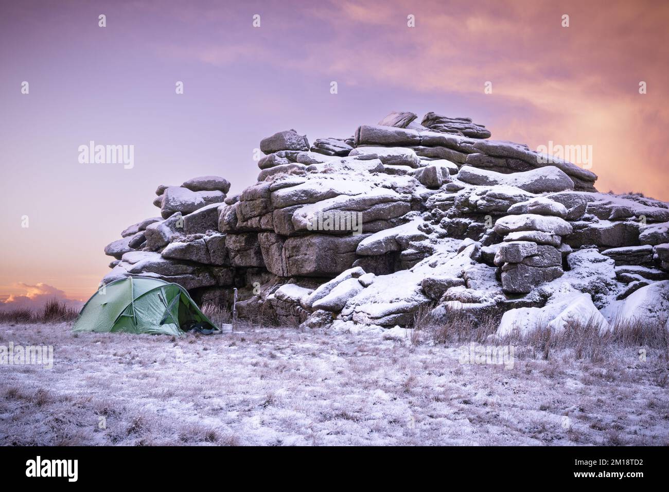Merrivale, Dartmoor-Nationalpark, Devon, Großbritannien. 11.. Dezember 2022. UK Weather: Fire and Ice on Dartmoor. Das einsame Zelt eines tapferen „wilden Campers“, der am Fuße eines schneebedeckten Great Mis Tor ein Camp aufgebaut hat. Die Winterbedingungen werden sich diese Woche mit weiteren Schneeprognosen fortsetzen. Kredit: Celia McMahon/Alamy Live News Stockfoto