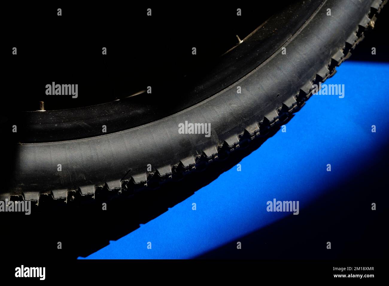 Mountainbike-Reifen auf blauem schwarzem Hintergrund mit Kopierbereich Stockfoto