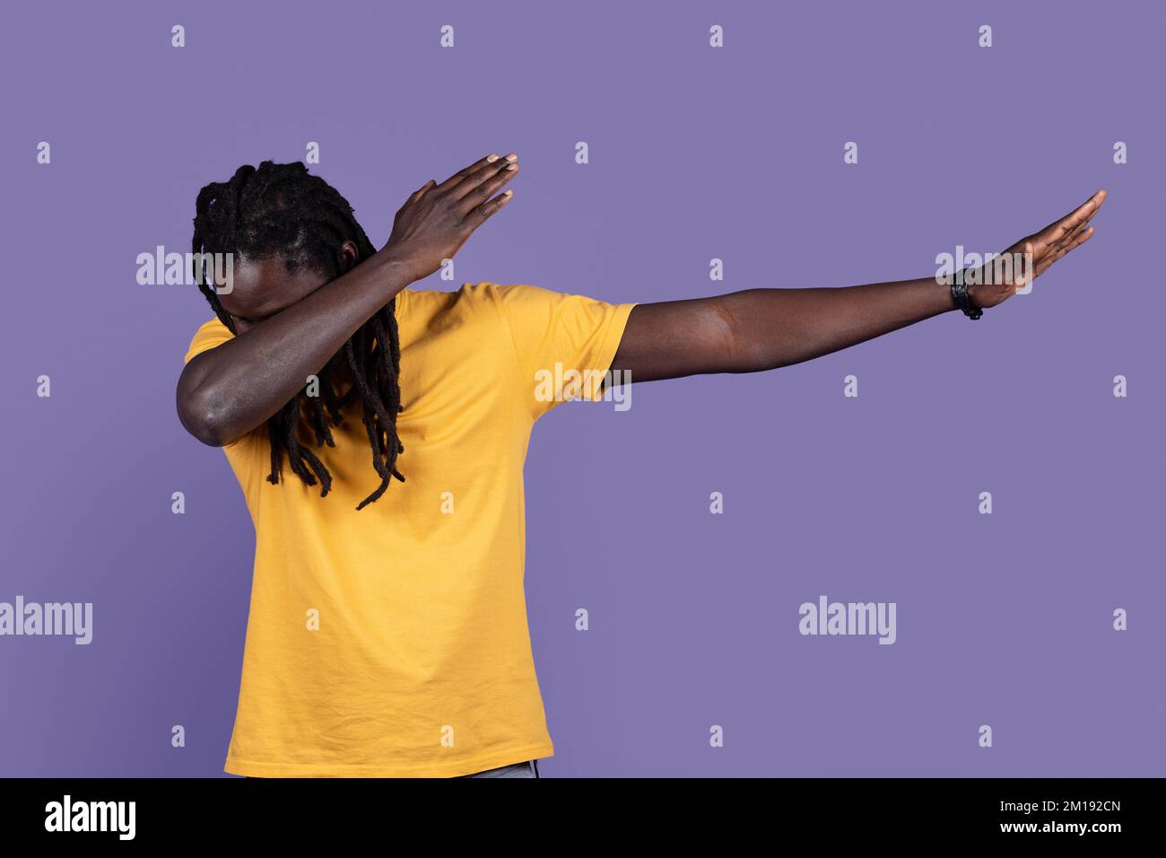 Ein cooler afrikanischer Mann in lässiger Optik, der Tanzbewegungen auf Lila zeigt Stockfoto