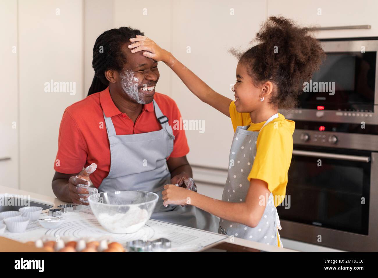 Fröhlicher Afroamerikanischer Vater Und Tochter, Die Spaß Haben, Während Sie In Der Küche Backen Stockfoto