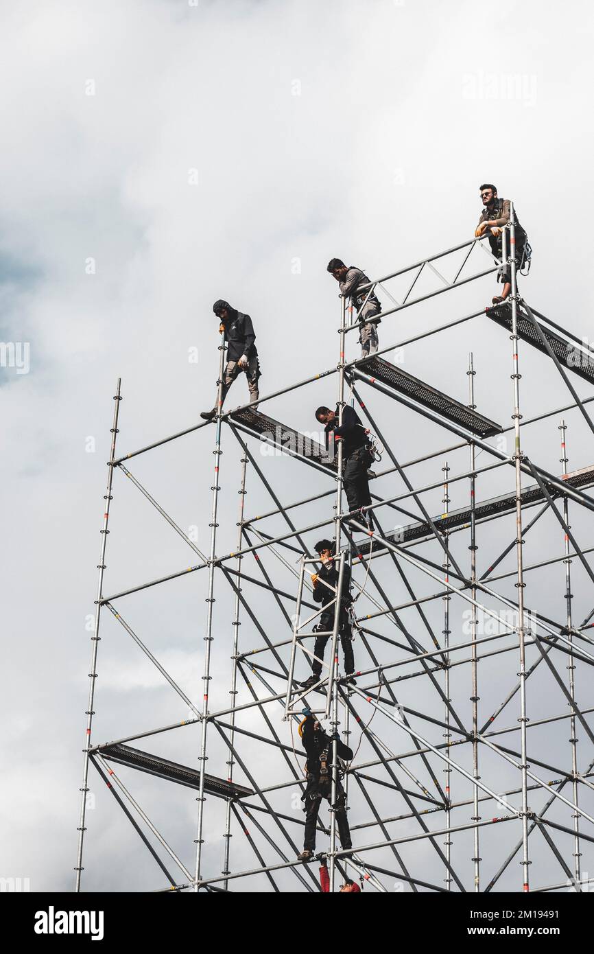 Arbeiter klettern auf ein Gerüst, während sie alle Sicherheitsmaßnahmen befolgen Stockfoto