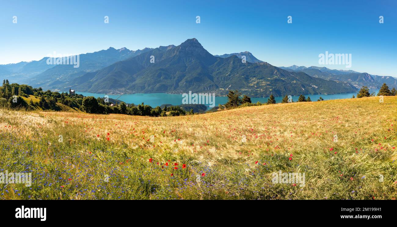 Sommerblick auf den Serre-Poncon Lake mit Grand Morgon Peak und dem Dorf Savines-le-Lac. Hautes-Alpes (Alpen). Frankreich Stockfoto