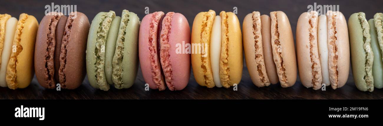 Süße und bunte französische Makronen auf einem dunklen Holztisch, Dessert. Panorama Stockfoto