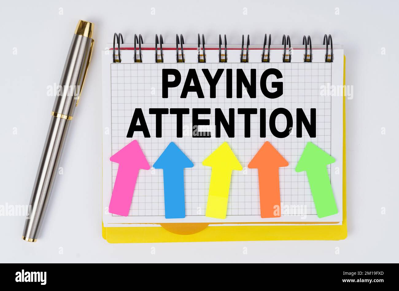Geschäfts- und Finanzkonzept. Legen Sie auf weißem Hintergrund einen Stift und ein Notizbuch mit der Aufschrift hin - PASSEN Sie AUF Stockfoto
