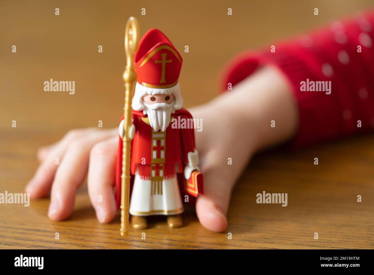 Kleine Kinderhand mit einer Duplo-Figur des Heiligen Nikolaus, Teil der germanischen Tradition am 6.. Dezember Stockfoto