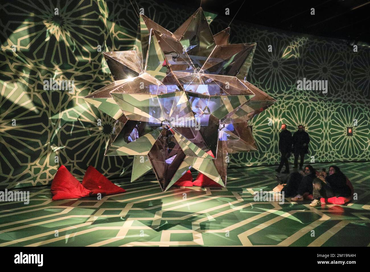 London, Großbritannien. 11.. Dezember 2022. Besucher sehen eine sternförmige extravagante Spiegelskulptur mit Innenprojektionen aus Filmfarsi. Der Kurvenraum im Barbican wurde in eine beeindruckende Galerie mit handbemalten Böden und Decken in islamischen Mustern für die Ausstellung „Rebel Rebel“ in Soheila Sokhanvari umgewandelt. Der iranische Künstler stellt kulturelle Figuren aus dem Iran in farbenfrohen Miniaturporträts dar. Die Ausstellung ist kostenlos und läuft bis zum 26. Februar 2023. Kredit: Imageplotter/Alamy Live News Stockfoto