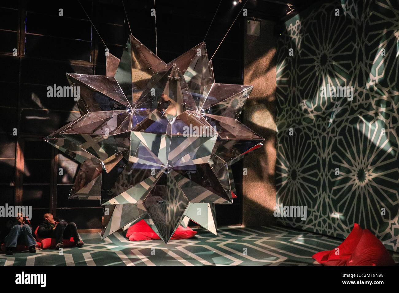London, Großbritannien. 11.. Dezember 2022. Besucher sehen eine sternförmige extravagante Spiegelskulptur mit Innenprojektionen aus Filmfarsi. Der Kurvenraum im Barbican wurde in eine beeindruckende Galerie mit handbemalten Böden und Decken in islamischen Mustern für die Ausstellung „Rebel Rebel“ in Soheila Sokhanvari umgewandelt. Der iranische Künstler stellt kulturelle Figuren aus dem Iran in farbenfrohen Miniaturporträts dar. Die Ausstellung ist kostenlos und läuft bis zum 26. Februar 2023. Kredit: Imageplotter/Alamy Live News Stockfoto
