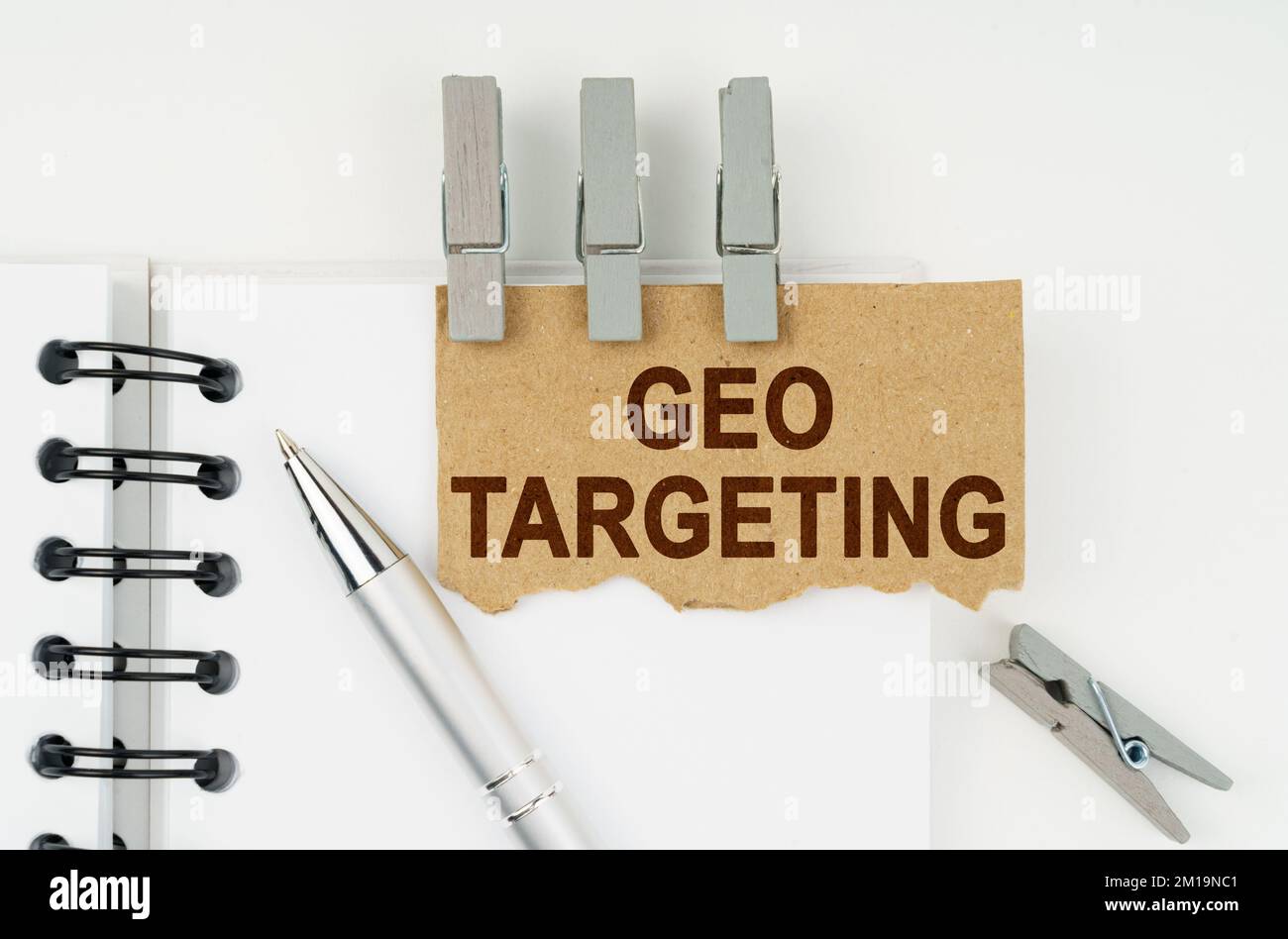 Geschäfts- und Finanzkonzept. Auf weißem Hintergrund befinden sich ein Notizbuch, ein Stift, Wäscheklammern und ein Karton mit der Aufschrift „Geo Targeting“ Stockfoto