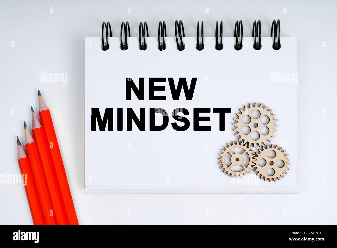 Geschäfts- und Finanzkonzept. Auf weißem Hintergrund befinden sich rote Stifte, Zahnräder und ein Notizbuch mit der Aufschrift „NEW MINDSET“ Stockfoto