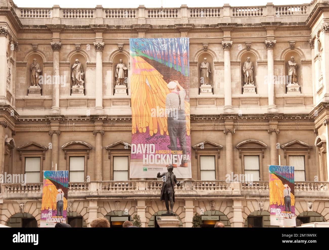 Royal Academy of Arts, Burlington House, Piccadilly, Mayfair, London, UK - Poster zur Ankündigung der David Hockney Ausstellung. Die Massen warten darauf, die Exspiration zu sehen Stockfoto