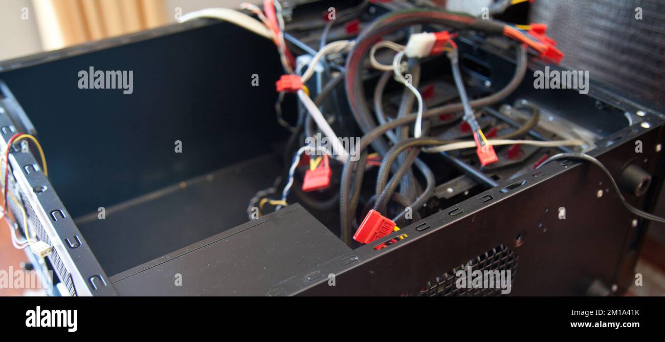 Desktop-Computer, schwarzes leeres Gehäuse und verschiedene Kabel, die versucht werden, in einer häuslichen Umgebung montiert zu werden Stockfoto