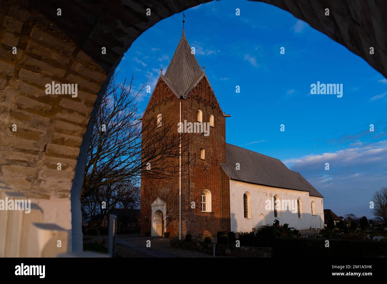 Die St.-Nikolaus-Kirche in Ballum Sogn wird bei Sonnenuntergang im dezember in Dänemark in orangefarbenes Licht getaucht Stockfoto