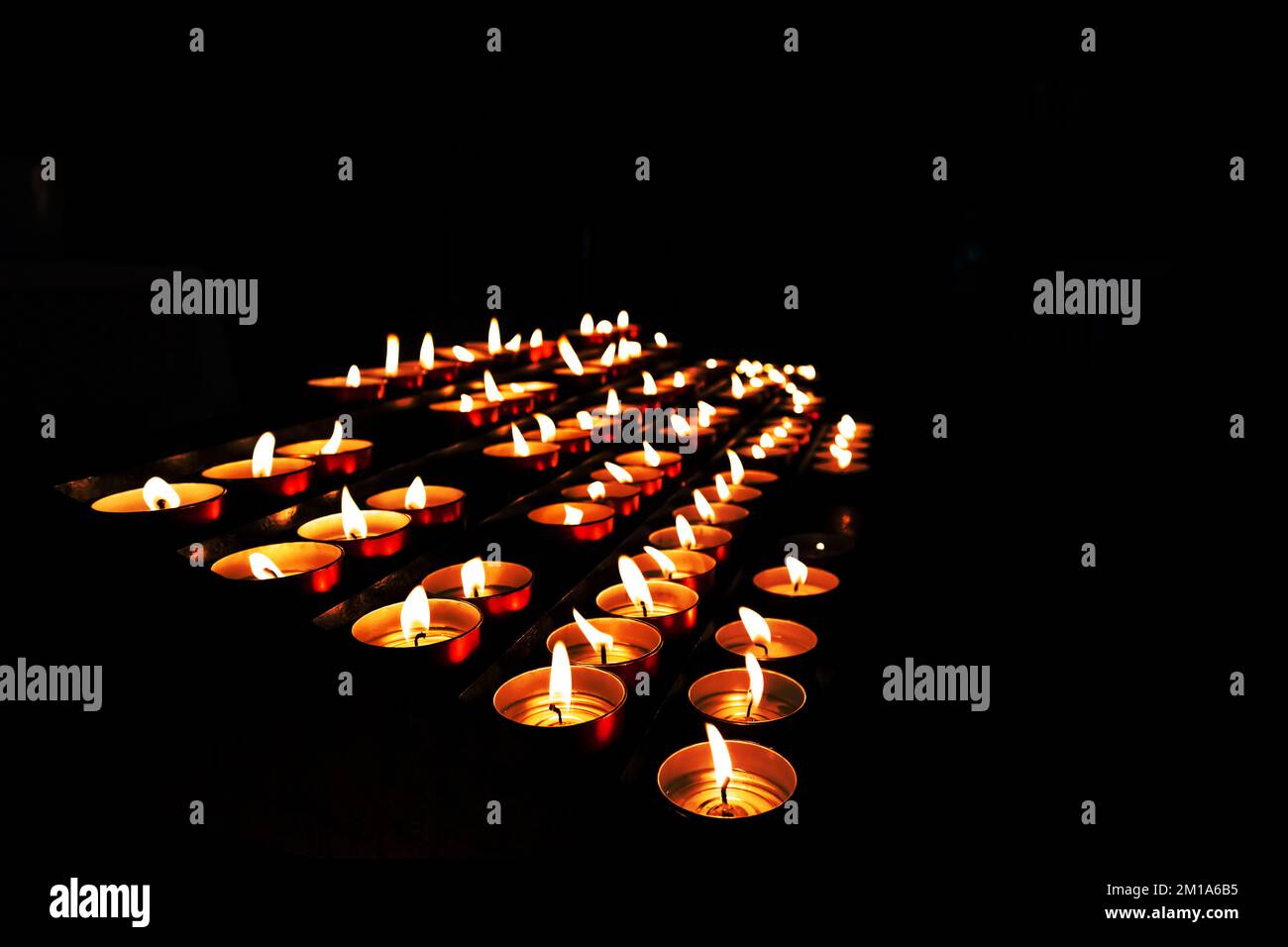 Ein schwarzer Hintergrund mit vielen gelben Kerzen Stockfoto