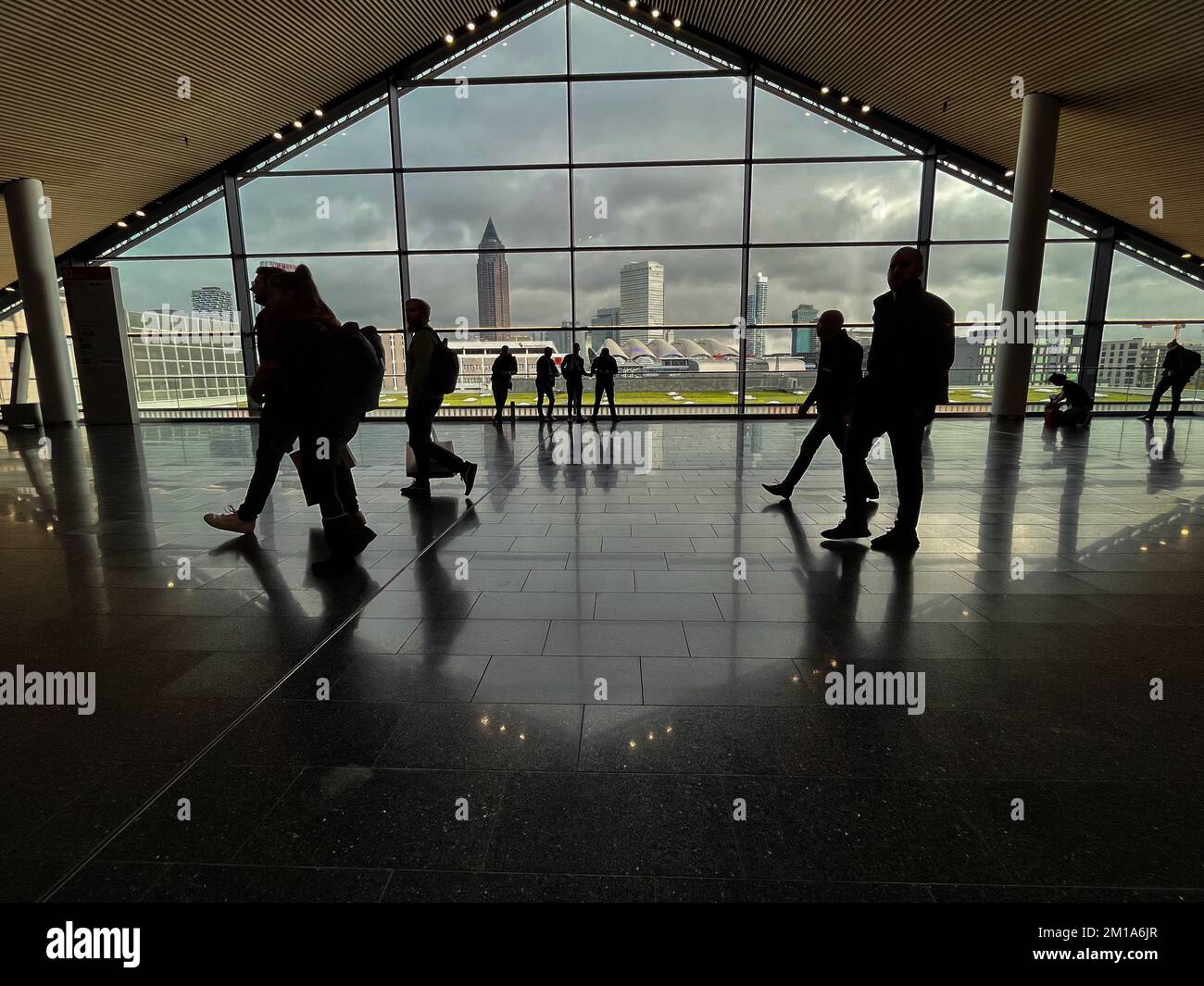 Menschen, die in einem modernen Gebäude mit der Frankfurter Stadt im Hintergrund spazieren gehen. Stockfoto