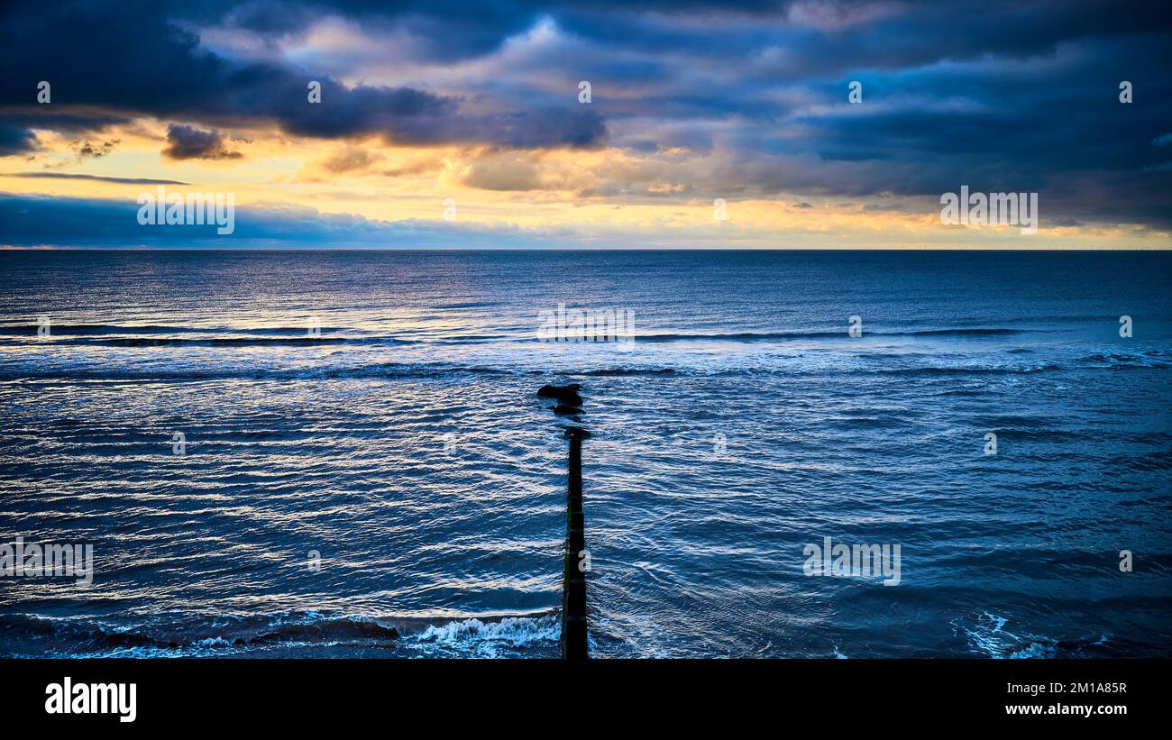 Winteruntergang über dem Meer und hölzerne Groyne an der Nordwestküste Englands Stockfoto