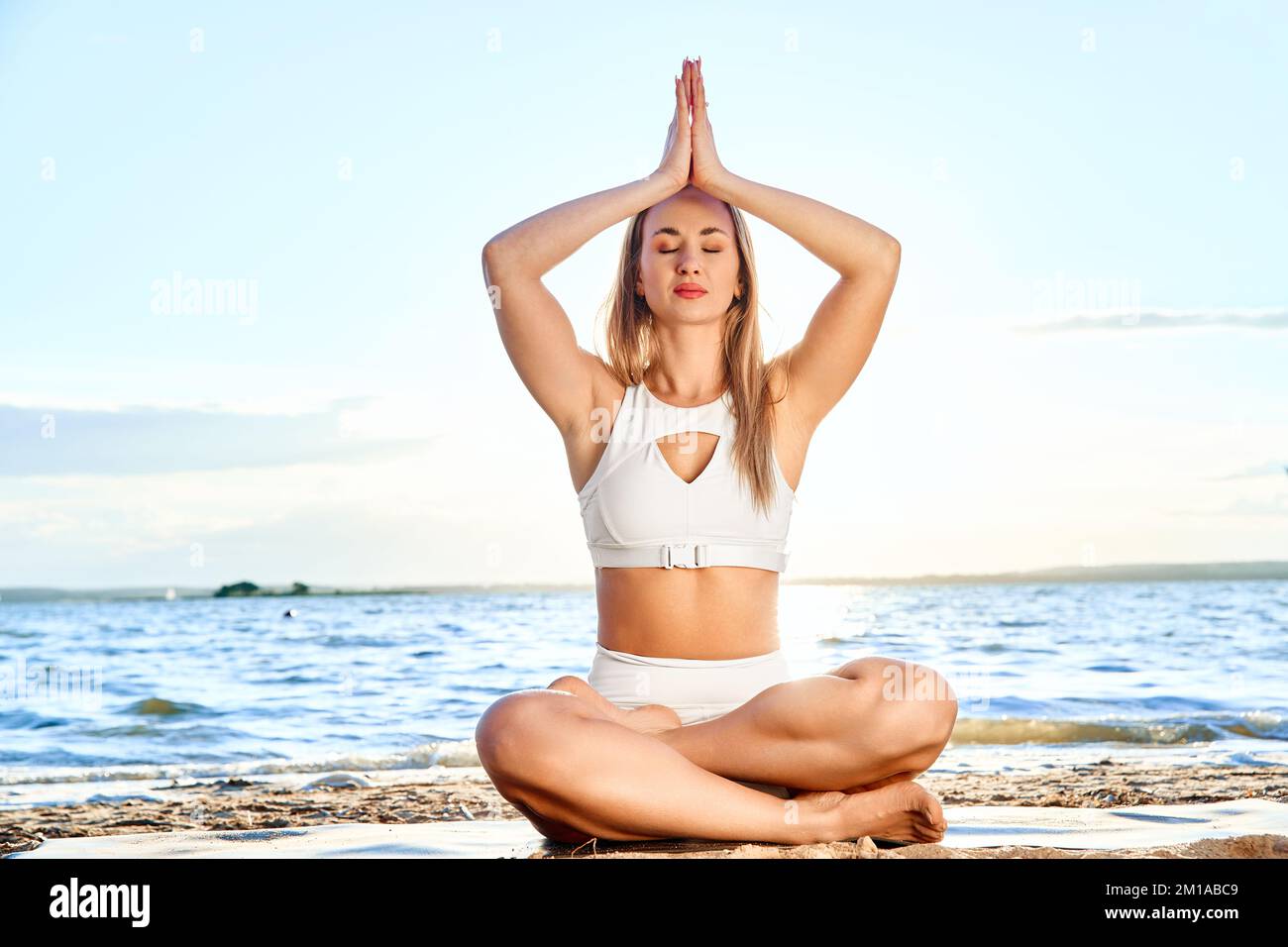 Junge Frau, die Yoga-Übungen macht. Gekreuzte Beine. Ruhig sitzen. Stockfoto