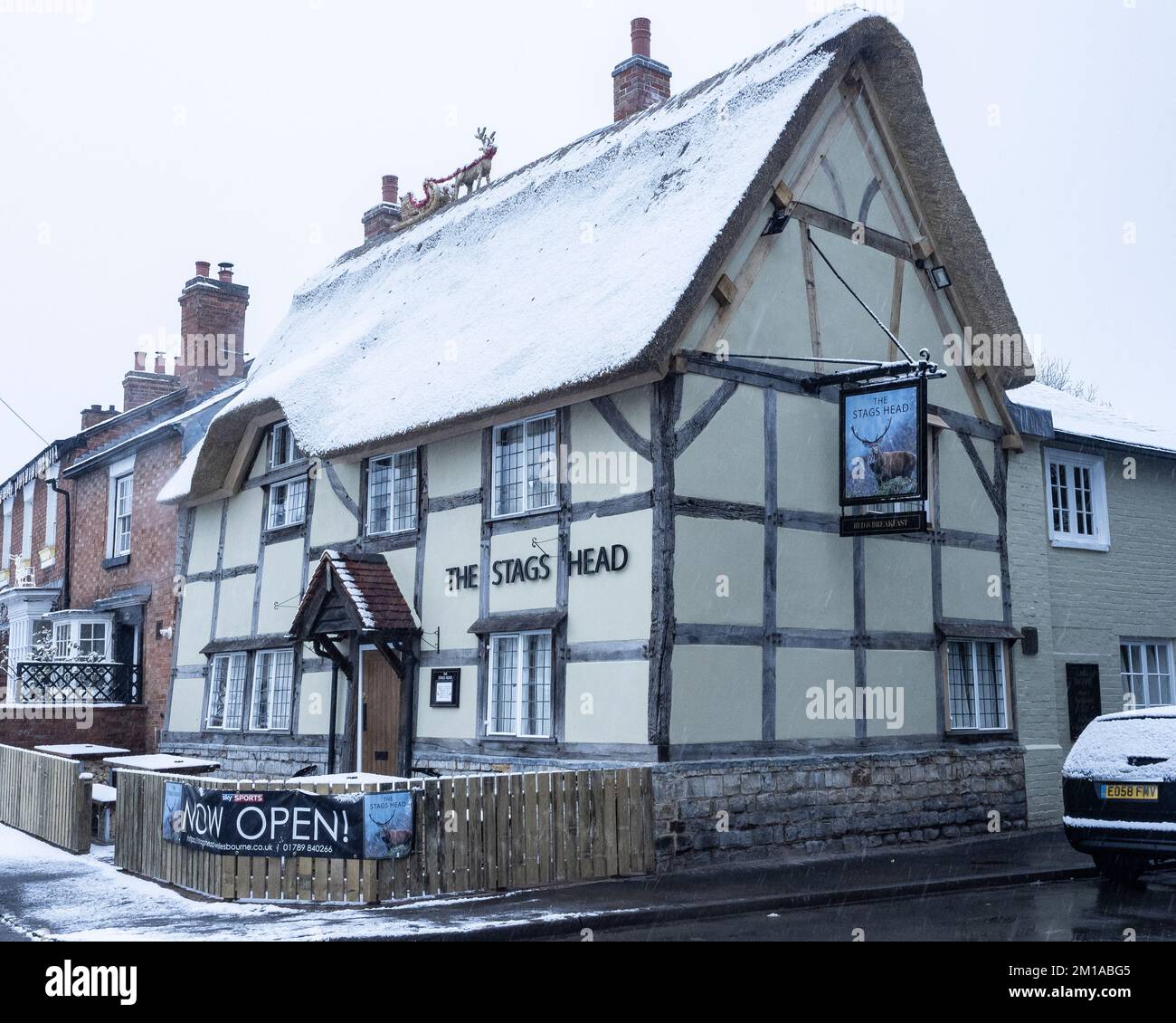 The Stag's Head, ein strohgedeckter und halbholzbedeckter Pub, der im Winter mit Schnee bedeckt ist. Stockfoto