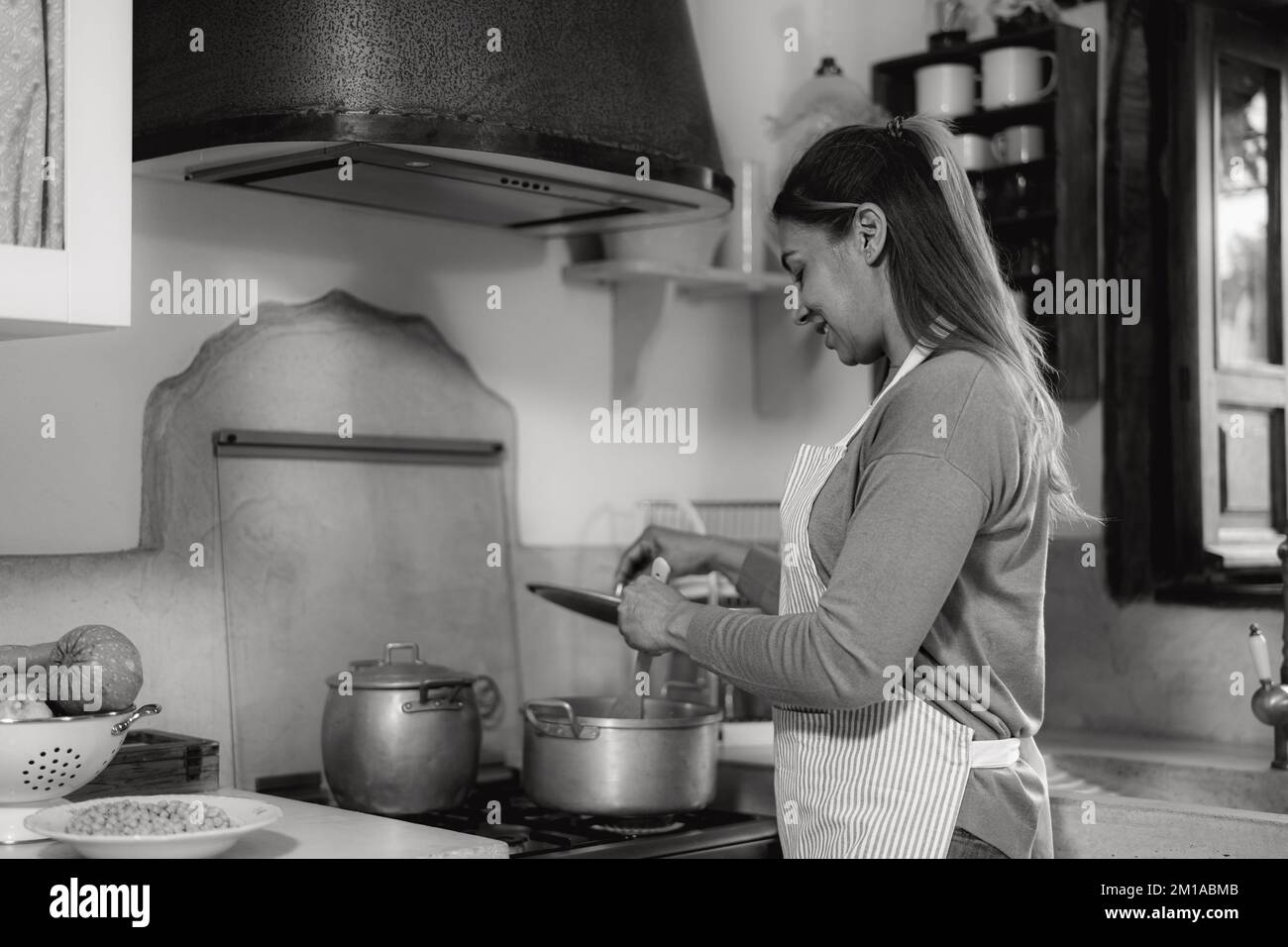 Lateinische Frau bereitet Speiserezept in ihrem Haus zu - Schwarz-Weiß-Schnitt Stockfoto
