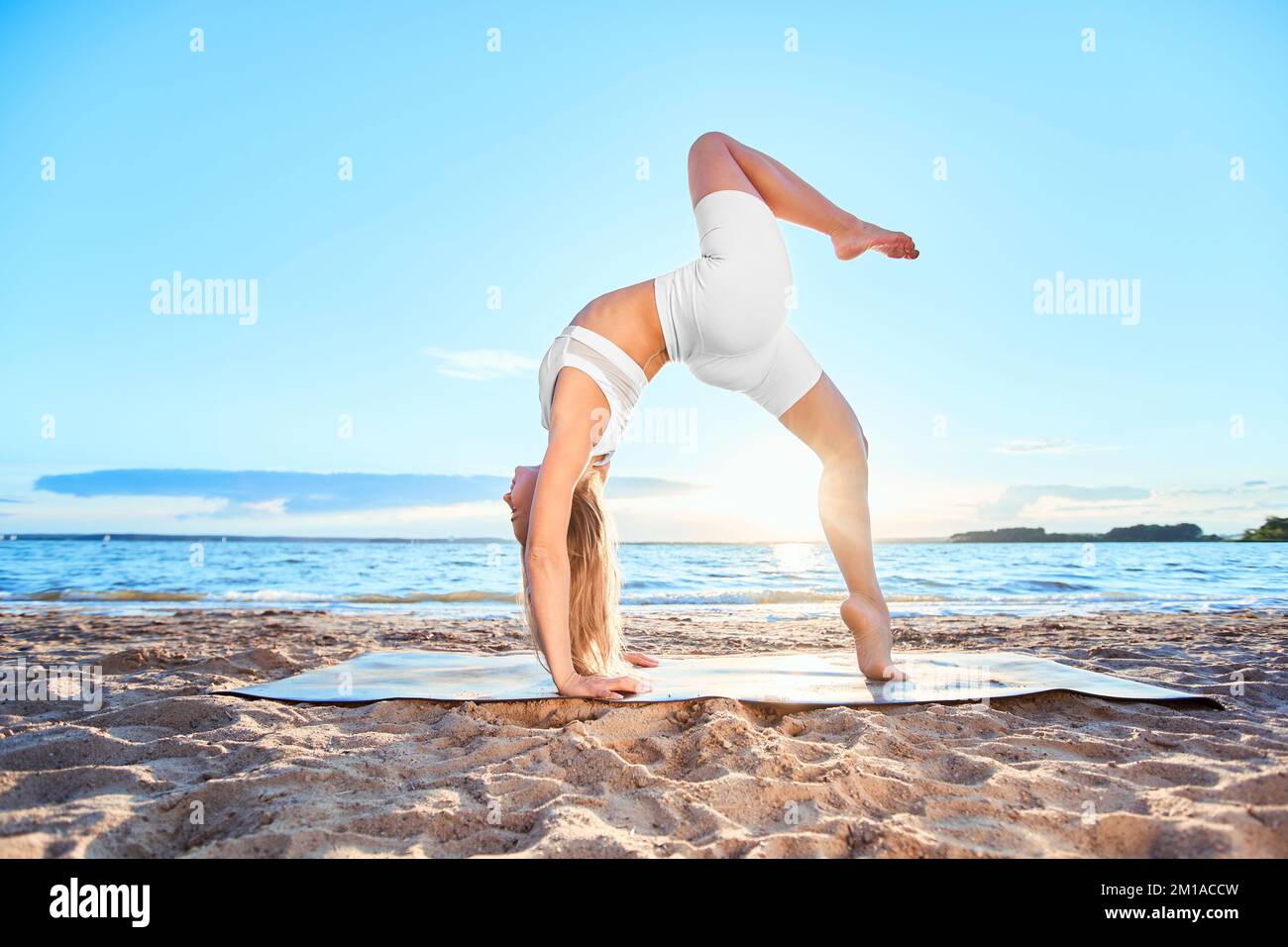 Junge Frau, die Yoga in der Nähe des Flusses praktiziert Stockfoto