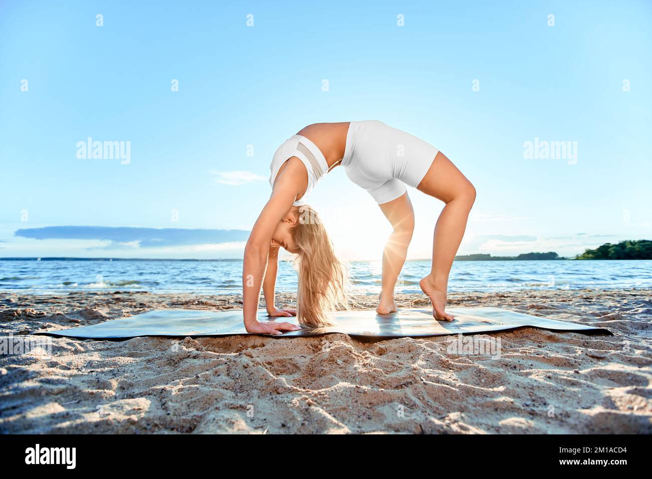 Junge Frau, die im Freien Yoga praktiziert. Die Radposition, Dhanurasana. Stockfoto