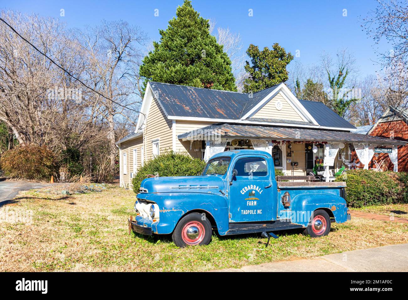 HILLSBOROUGH, NC, USA - 29. NOVEMBER 2022: Antiquitätengeschäft, „Uniquitiques“, in einem alten Haus mit altem Pickup-Truck vor dem Hof. Stockfoto
