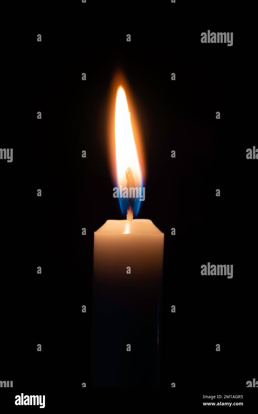 Ein einzelner Kerzenstab, der auf schwarzem Hintergrund hell brennt Stockfoto