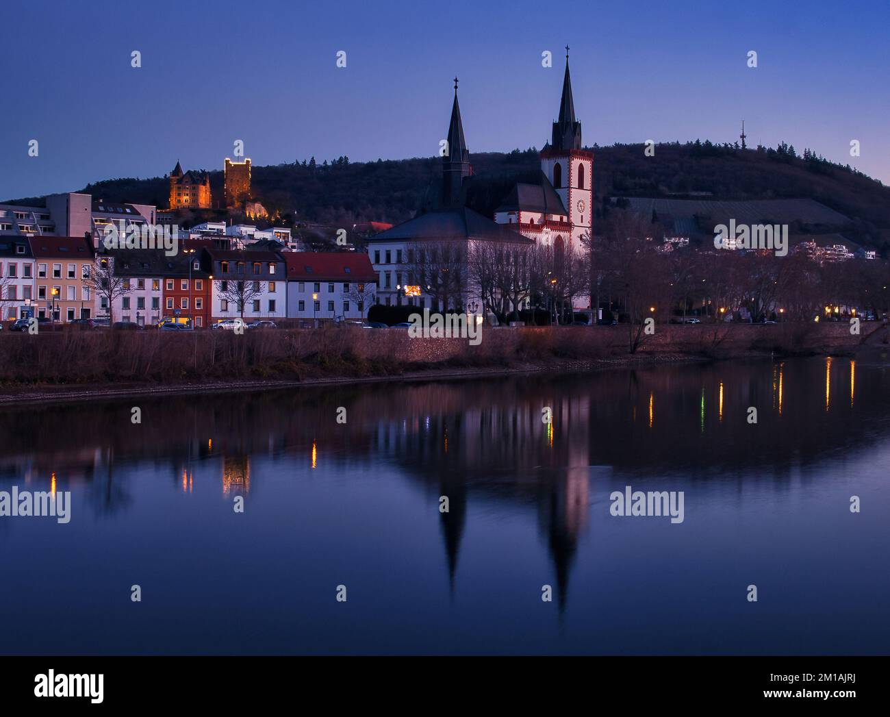 Bingen am Rhein, Deutschland - 10. Januar 2021: Die Basilika St. Martin Kirche und andere Gebäude neben dem Rhein und Schloss Klopp beleuchtet Stockfoto