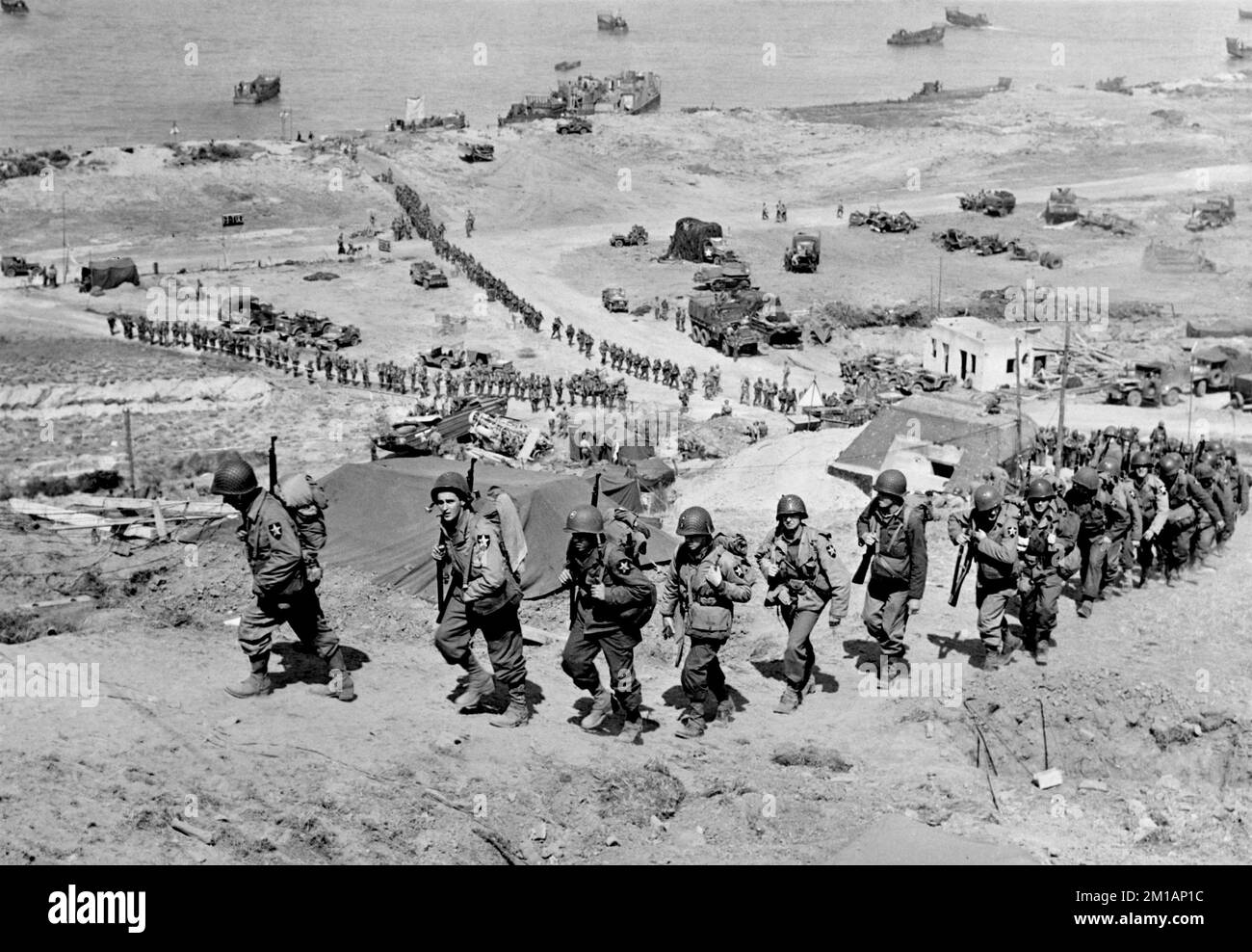 OMAHA BEACH, NORMANDIE, FRANKREICH - 07. Juni 1944 - Truppen der US Army 2. Infanterie Division marschieren beim E-1-Draw im Easy Red Sektor hoch Stockfoto